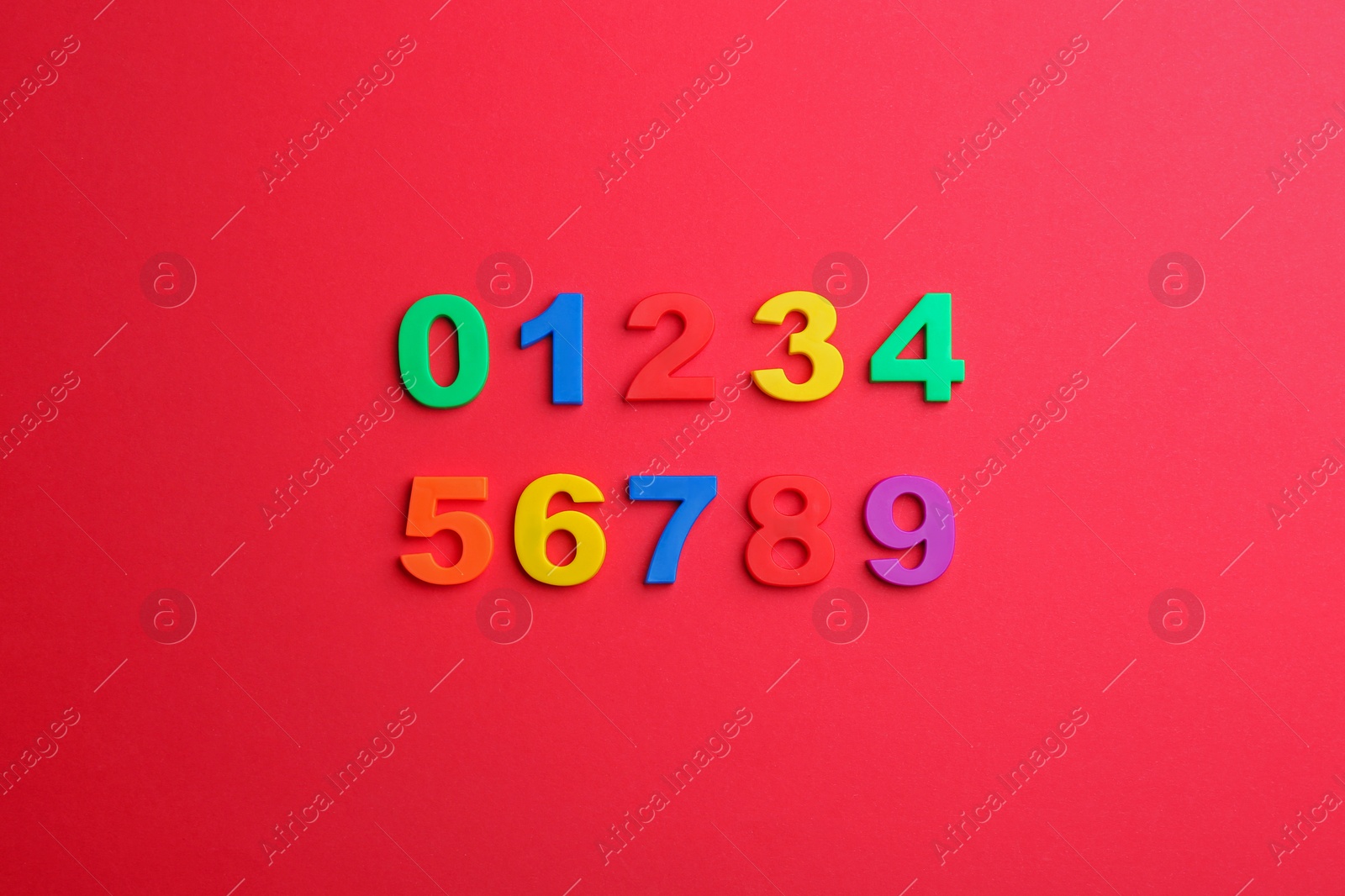 Photo of Colorful magnetic numbers on red background, flat lay