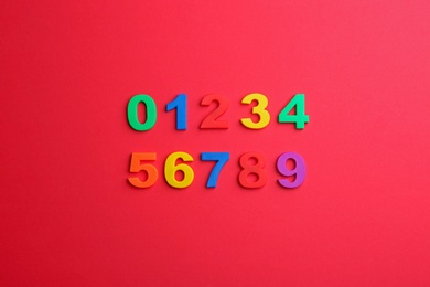 Colorful magnetic numbers on red background, flat lay