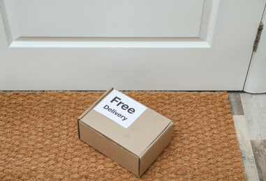 Parcel with sticker Free Delivery on rug indoors. Courier service