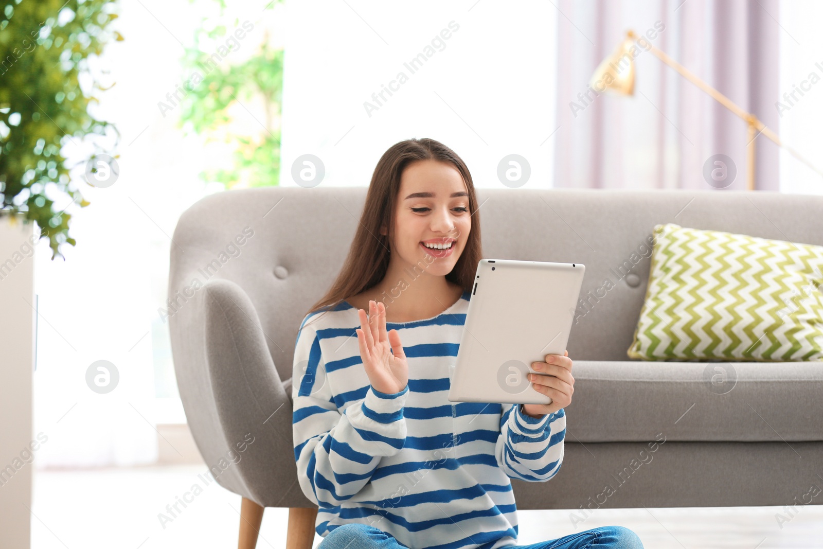 Photo of Woman using tablet for video chat in living room