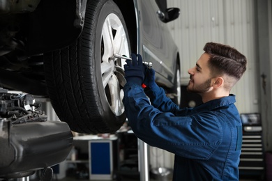 Photo of Technician working with car in automobile repair shop