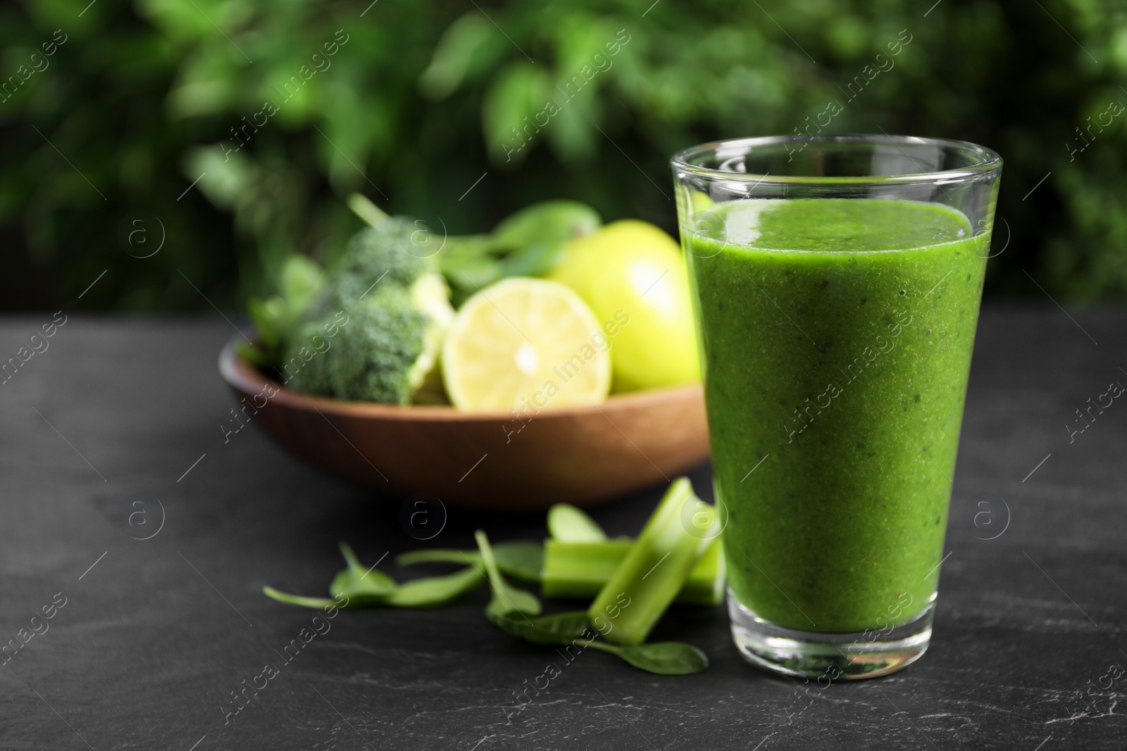 Photo of Delicious fresh green juice on black table. Space for text