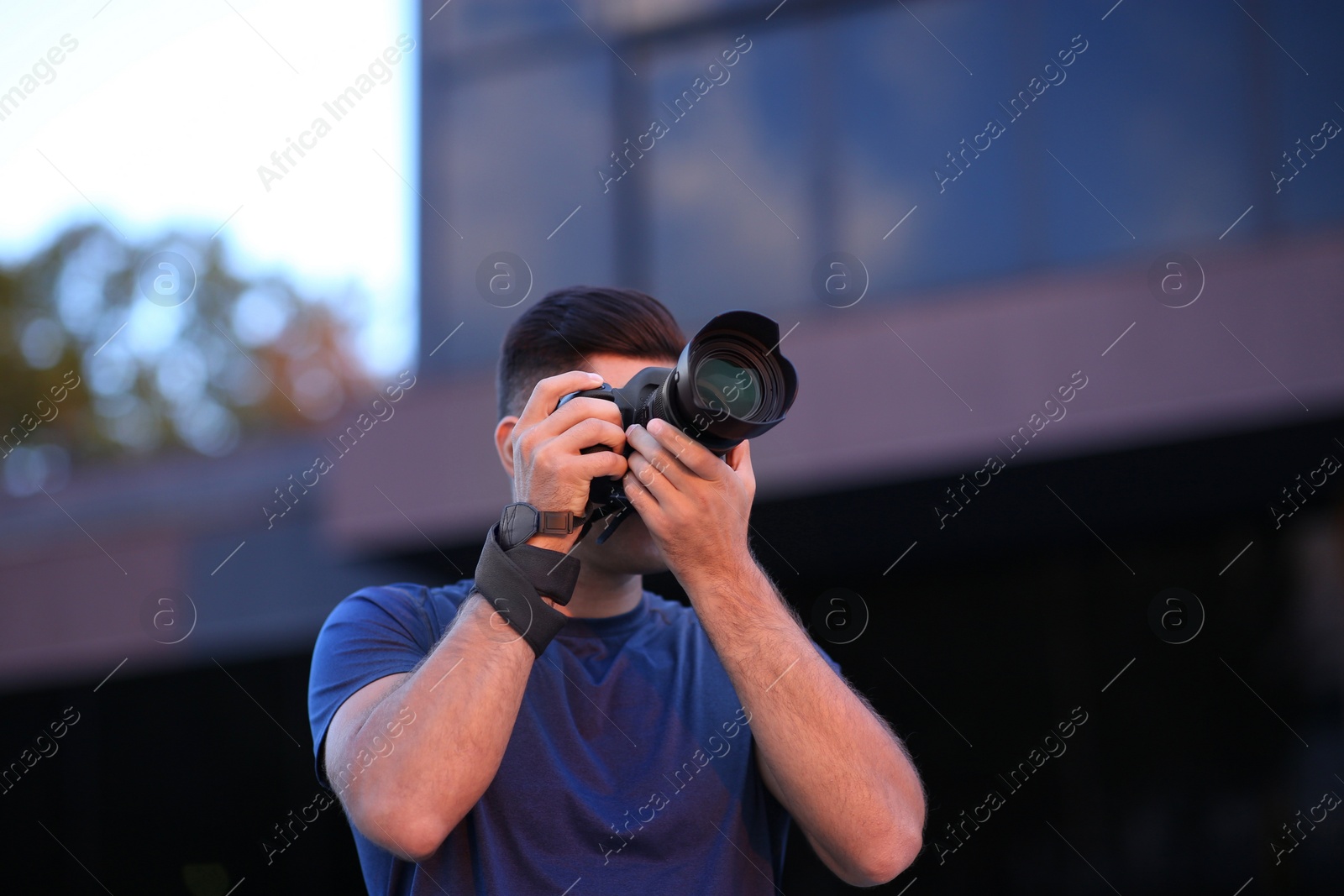 Photo of Photographer taking picture with professional camera on city street in evening