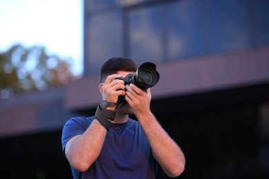 Photographer taking picture with professional camera on city street in evening