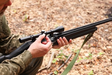 Photo of Man with hunting rifle wearing camouflage outdoors, closeup