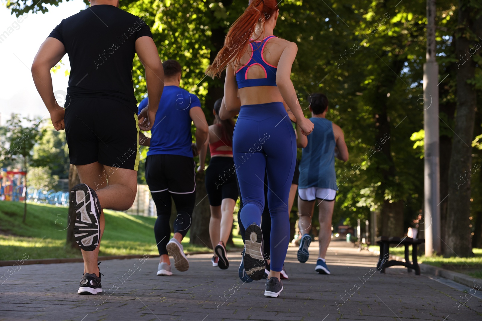 Photo of Group of people running in park, back view