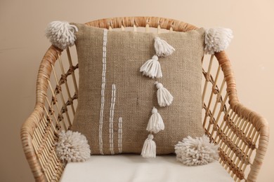 Stylish soft pillow on armchair near beige wall