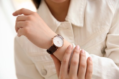 Woman with luxury wristwatch on blurred background, closeup