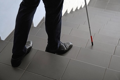 Photo of Blind person with long cane going down stairs, closeup