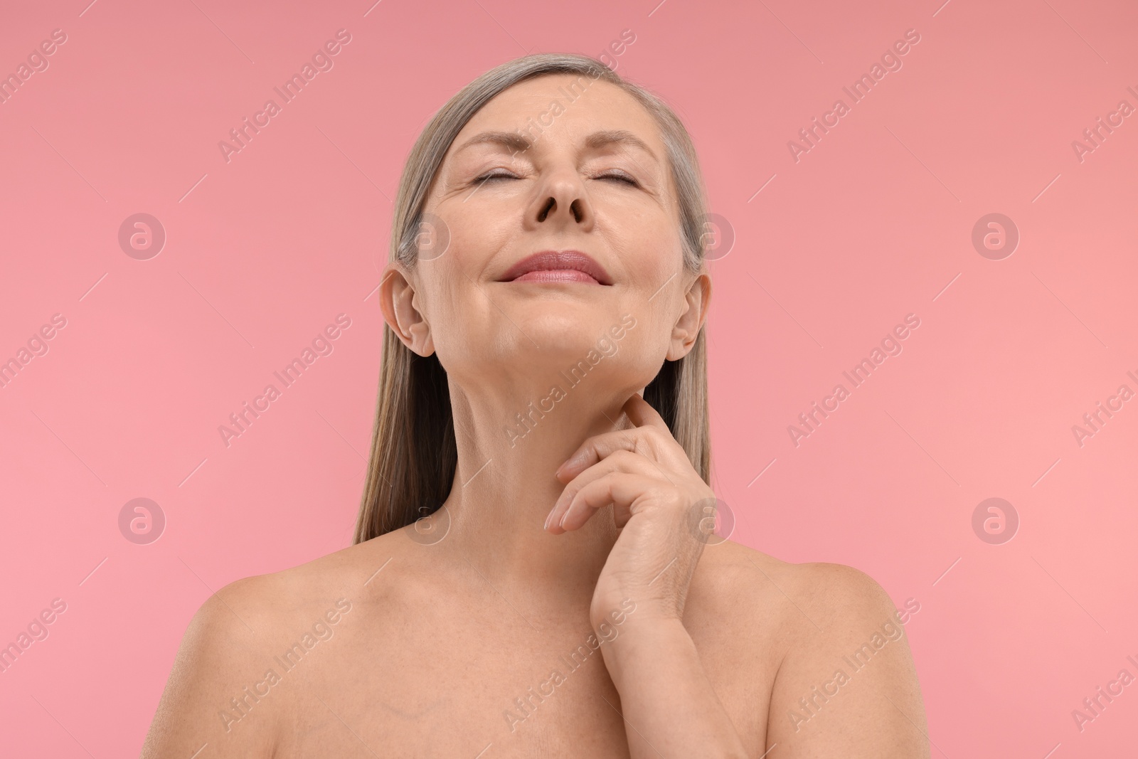 Photo of Beautiful woman touching her neck on pink background