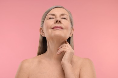 Photo of Beautiful woman touching her neck on pink background