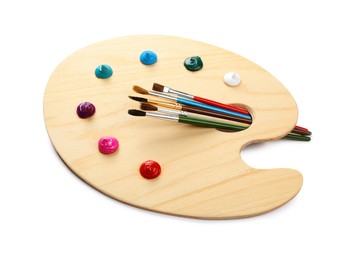 Photo of Wooden artist's palette with brushes and samples of paints isolated on white