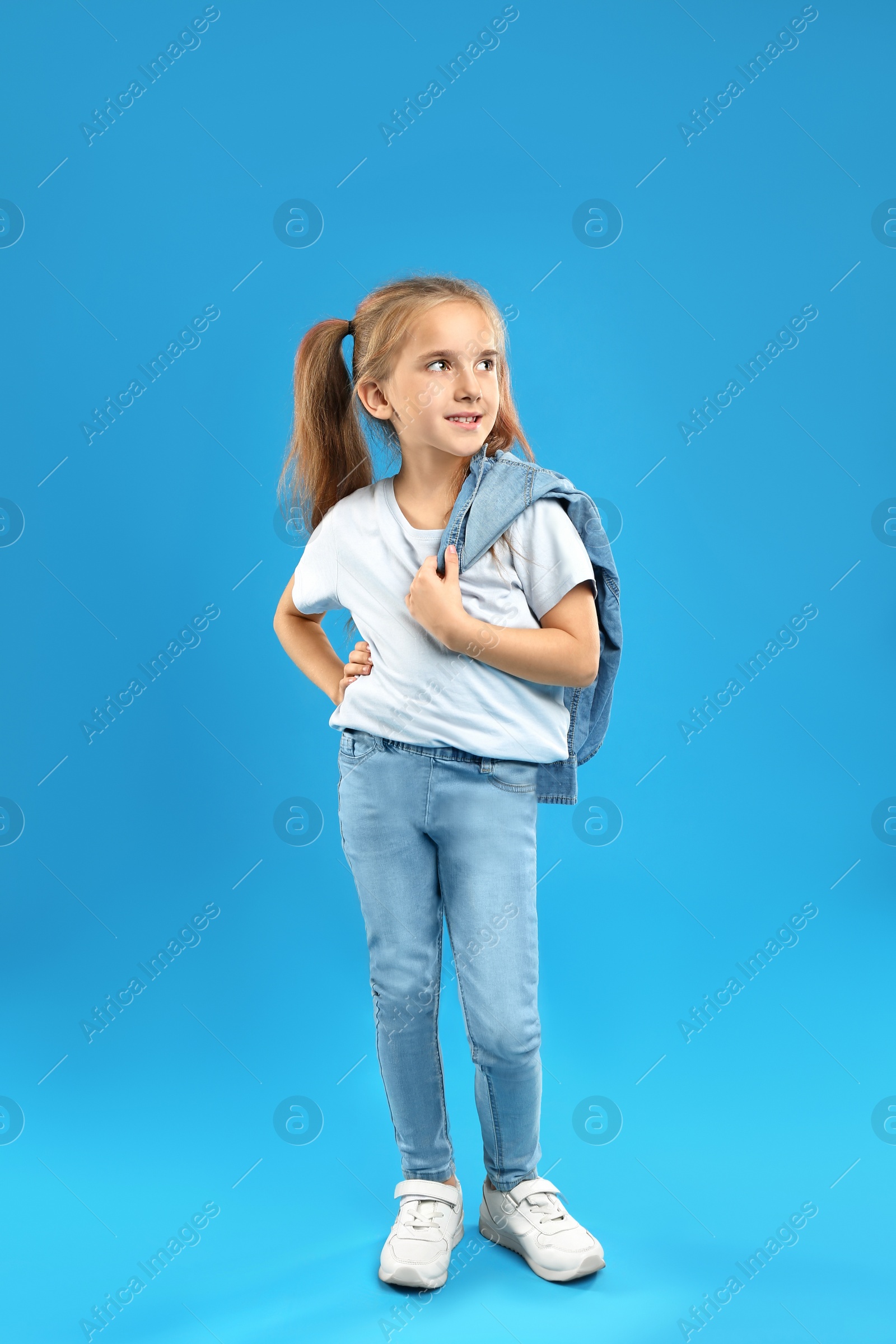 Photo of Cute little girl posing on blue background