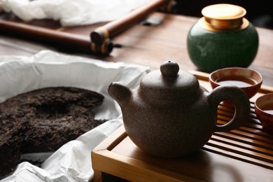 Teapot with pu-erh tea on wooden tray, closeup