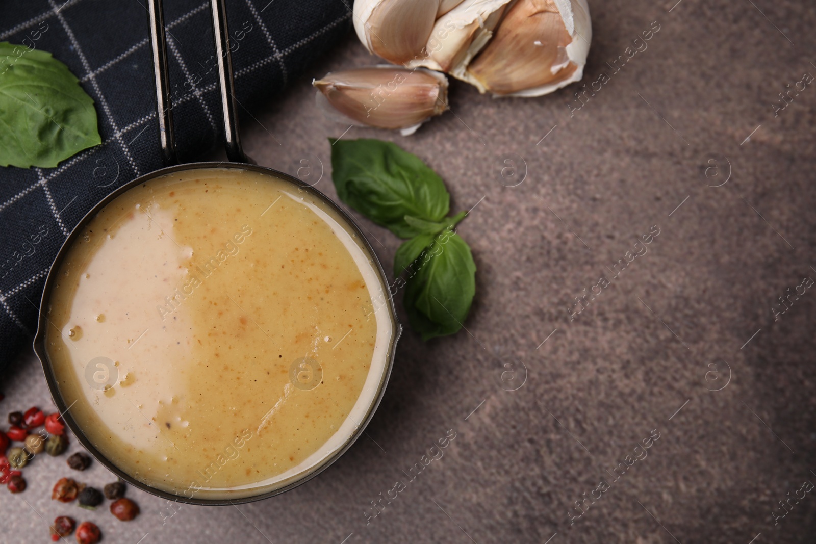 Photo of Delicious turkey gravy, basil, peppercorns and garlic on brown textured table, flat lay. Space for text