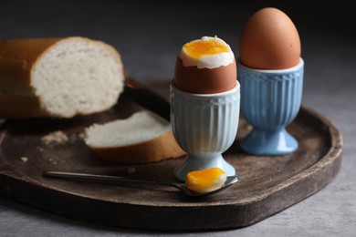 Tasty boiled chicken eggs with bread on grey table, closeup