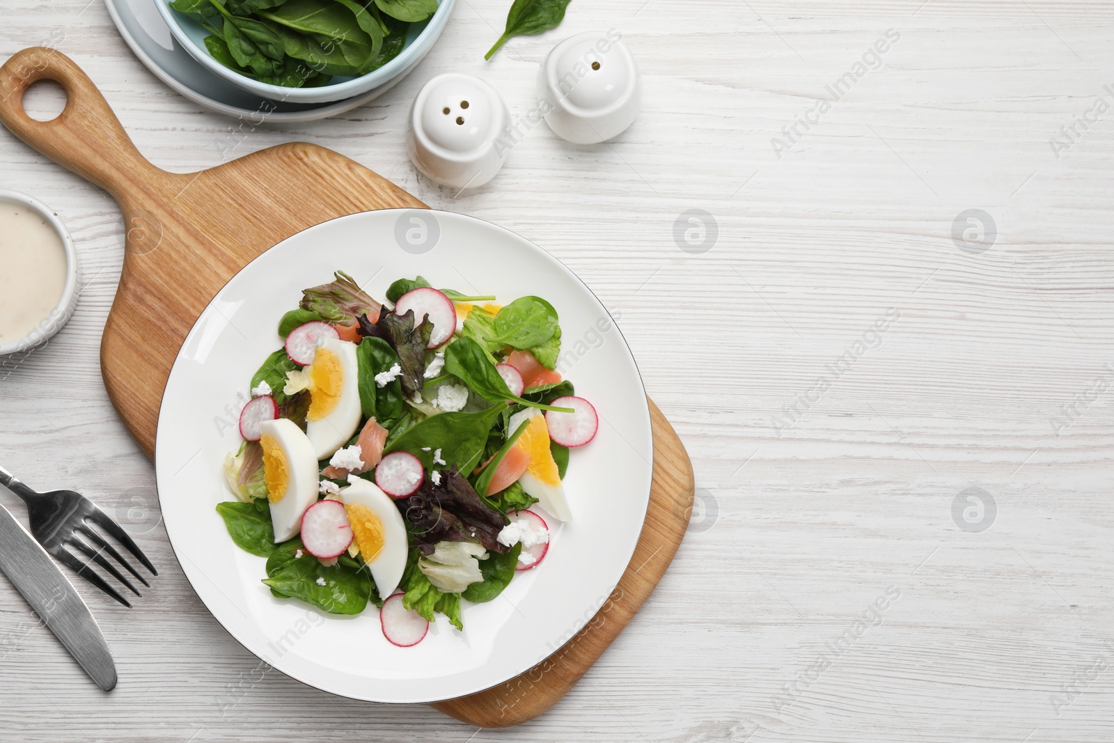 Photo of Delicious salad with boiled egg, radish and cheese served on white wooden table, flat lay. Space for text
