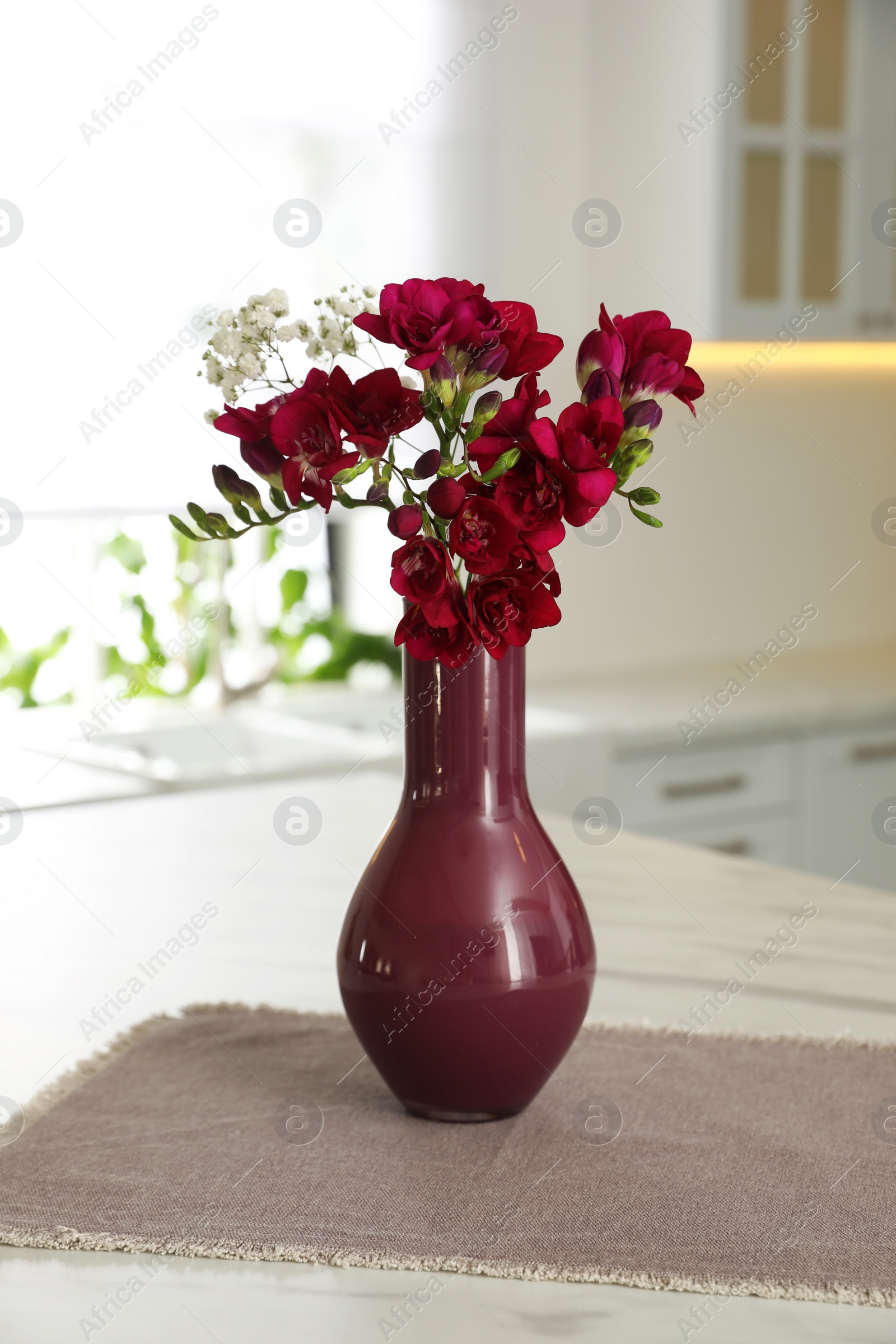 Photo of Beautiful bouquet with freesia flowers on table in kitchen