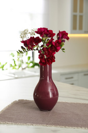 Photo of Beautiful bouquet with freesia flowers on table in kitchen