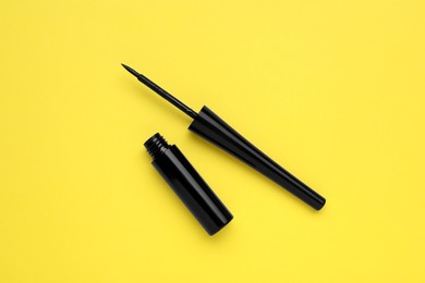 Black eyeliner on yellow background, flat lay. Makeup product