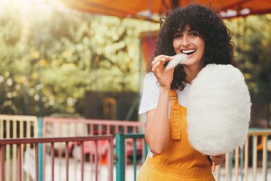 Image of Beautiful woman eating cotton candy outdoors on sunny day. Space for text