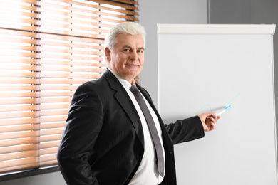 Photo of Senior business trainer near flip chart in office