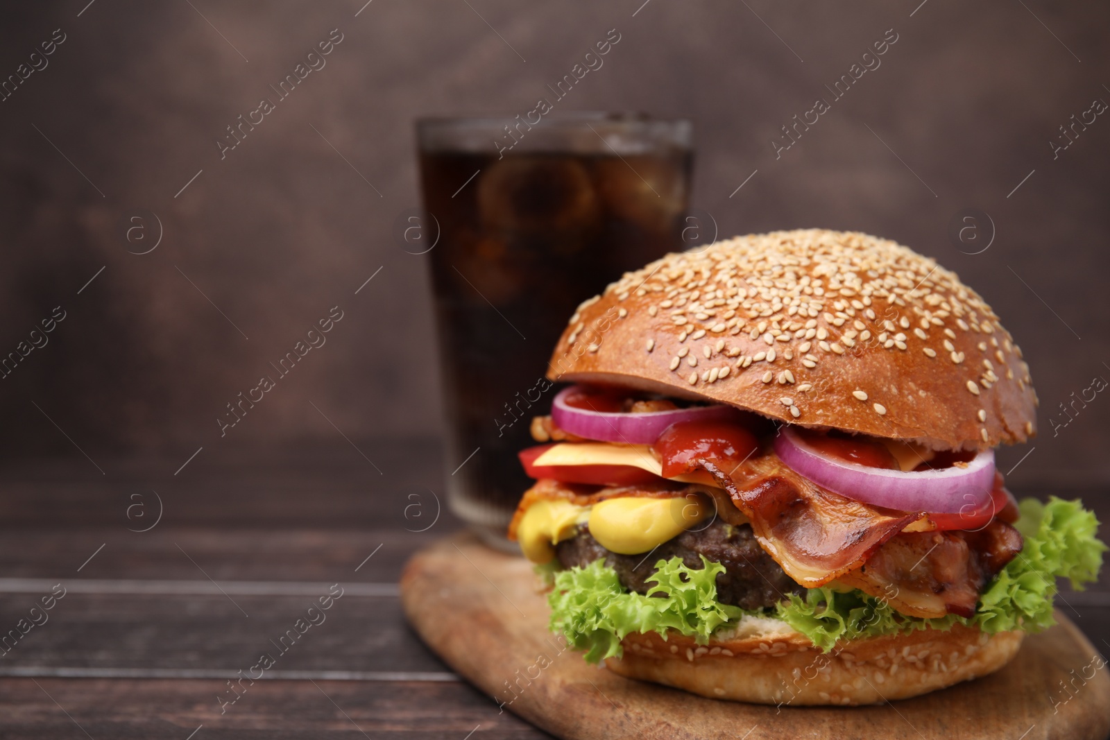 Photo of Delicious burger with bacon, patty and vegetables on wooden table, closeup. Space for text