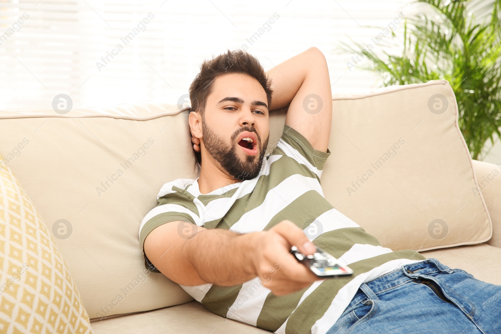 Photo of Lazy young man watching TV on sofa at home