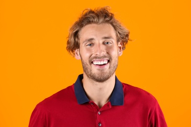 Photo of Handsome young man laughing on color background