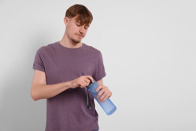 Photo of Man holding transparent plastic bottle with drink on light grey background. Space for text