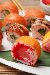Photo of Different delicious sushi rolls on white plate, closeup