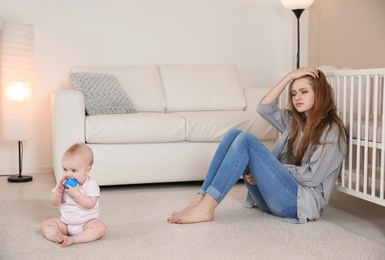 Photo of Young mother suffering from postnatal depression and cute baby girl at home