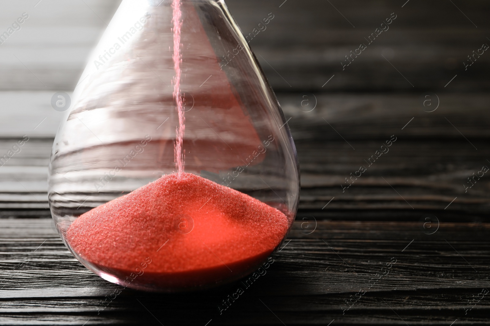 Photo of Hourglass with flowing sand on table, closeup. Time management