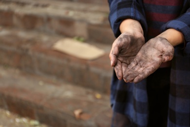 Photo of Poor homeless child begging for help outdoors, closeup