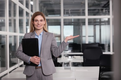 Photo of Happy real estate agent with leather portfolio indoors. Space for text