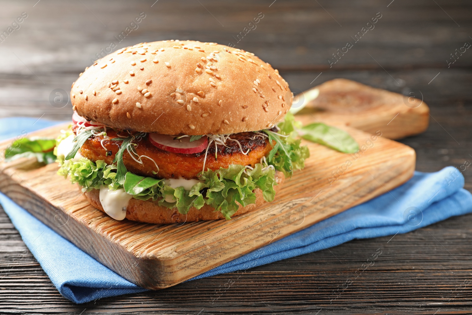 Photo of Board with tasty vegetarian burger on wooden table