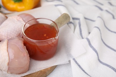 Photo of Fresh marinade and raw chicken drumsticks on table, closeup. Space for text