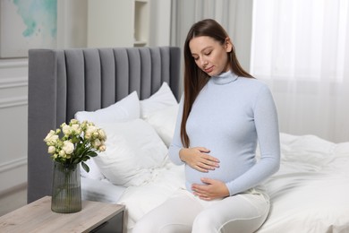 Beautiful pregnant woman with long hair in bedroom