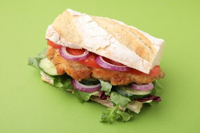 Photo of Delicious sandwich with schnitzel on green background, closeup