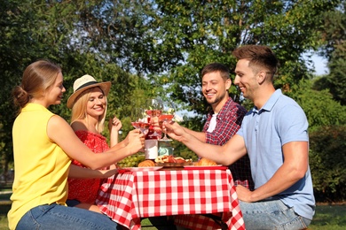 Group of people having picnic at table in park on summer day