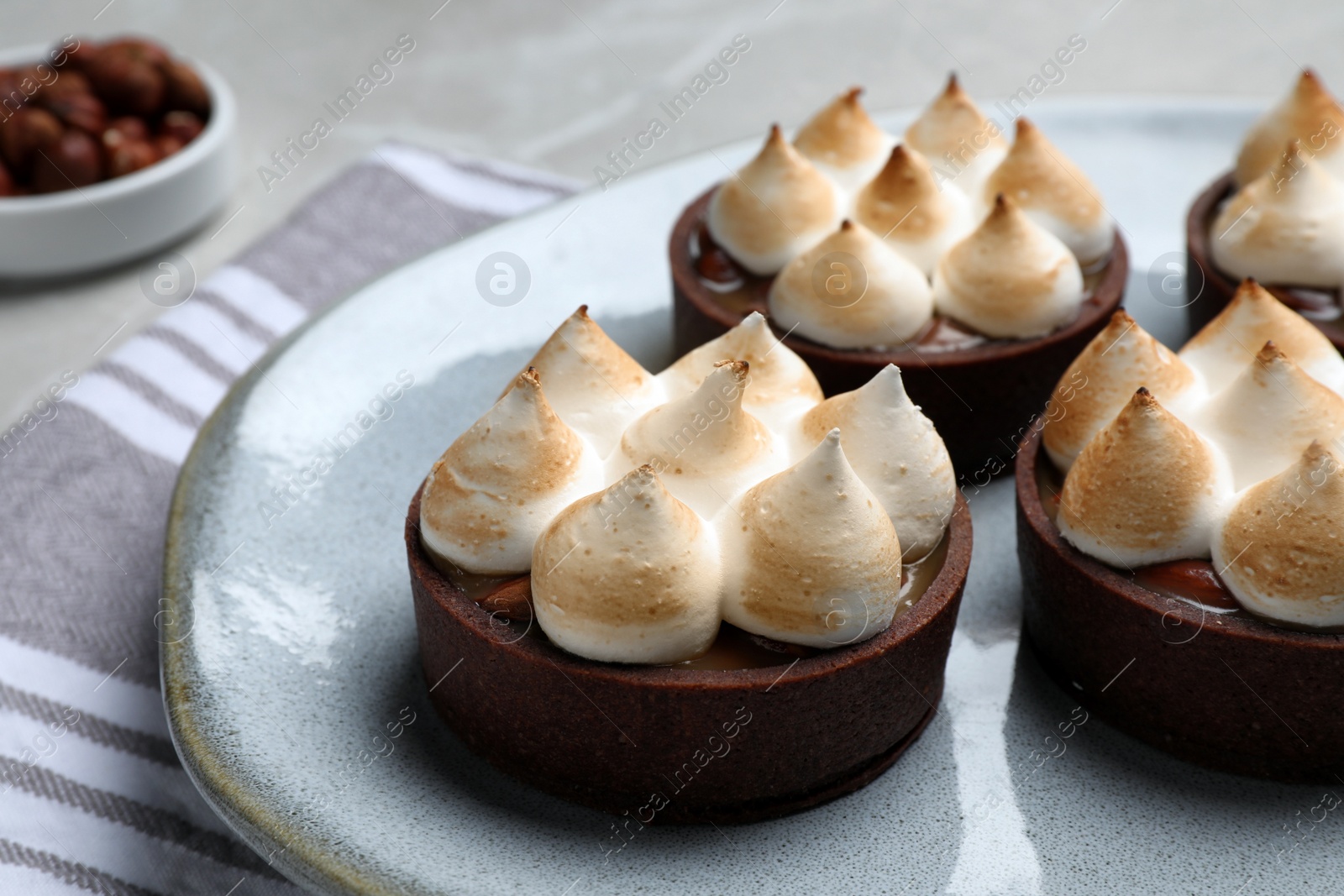 Photo of Delicious salted caramel chocolate tarts with meringue served on table, closeup