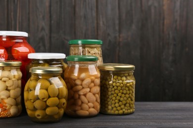 Photo of Glass jars with different pickled vegetables and mushrooms on wooden background