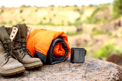 Sleeping bag, cup and boots outdoors on sunny day