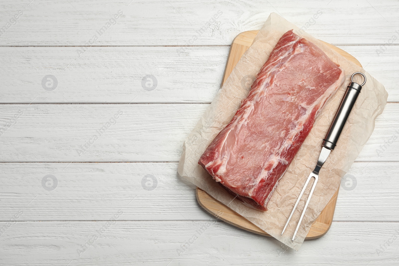 Photo of Tasty fresh pork meat on white wooden table, flat lay. Space for text