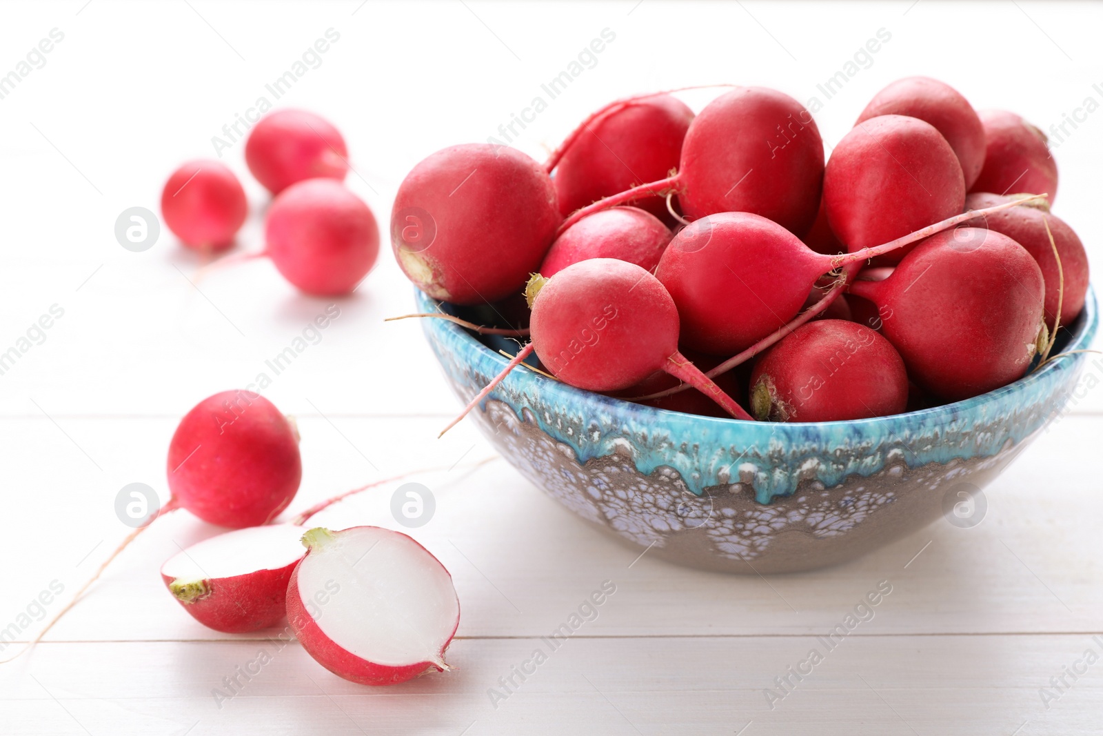 Photo of Bowl with fresh ripe radishes on white wooden table