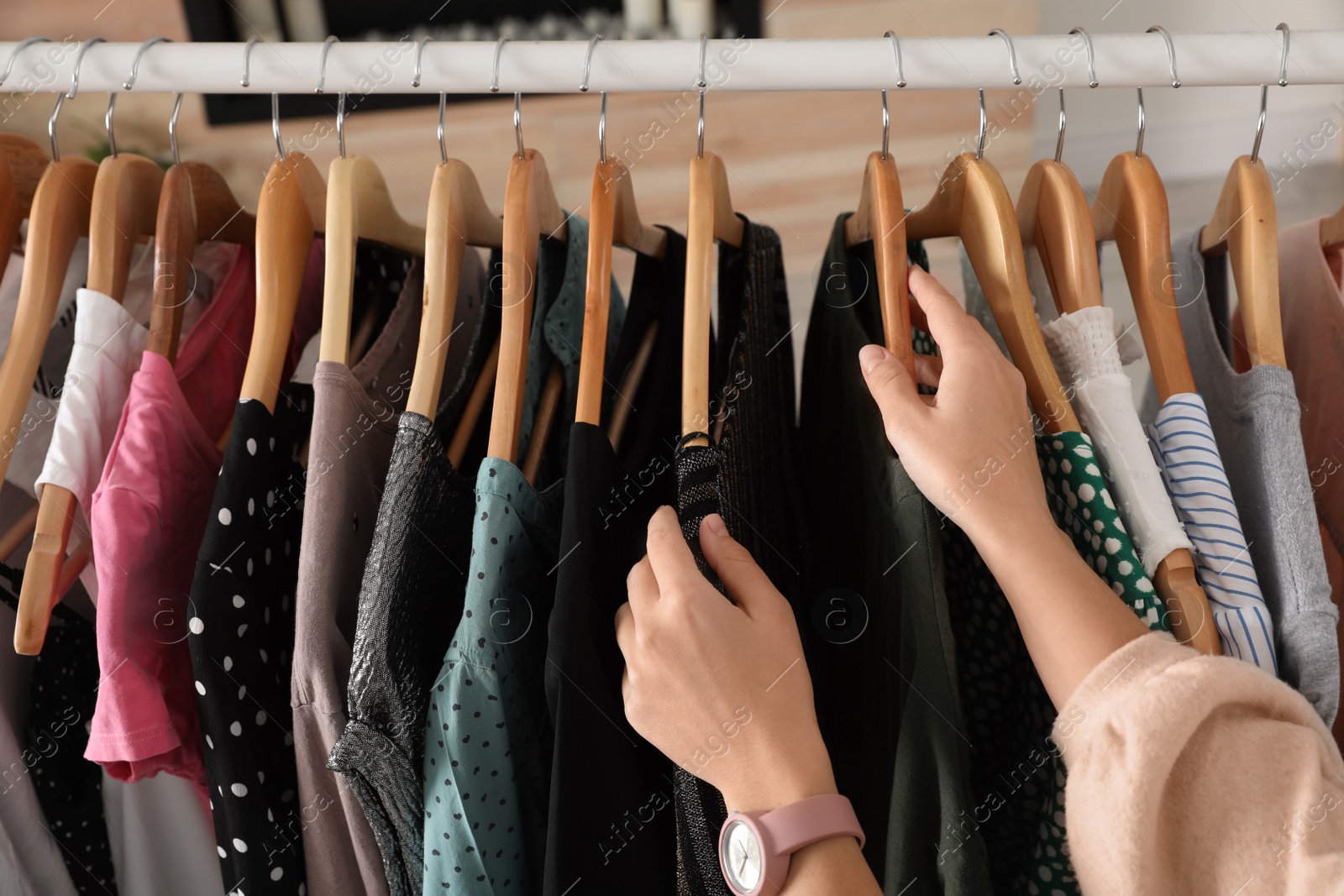 Photo of Woman choosing clothes from wardrobe rack, closeup