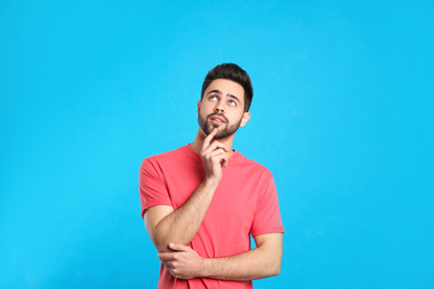 Photo of Pensive young man on light blue background. Thinking about difficult question