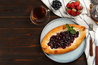 Photo of Delicious sweet cottage cheese pastry with cherry jam served on wooden table, flat lay. Space for text