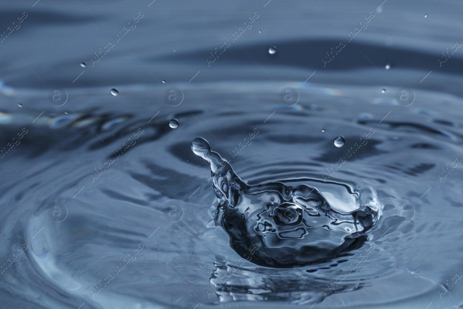 Photo of Splash of clear water with drops on dark blue background, closeup