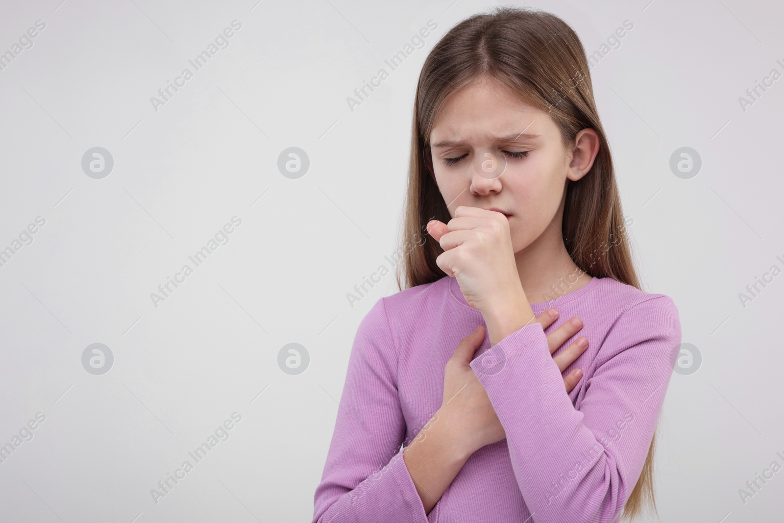 Photo of Sick girl coughing on light background, space for text